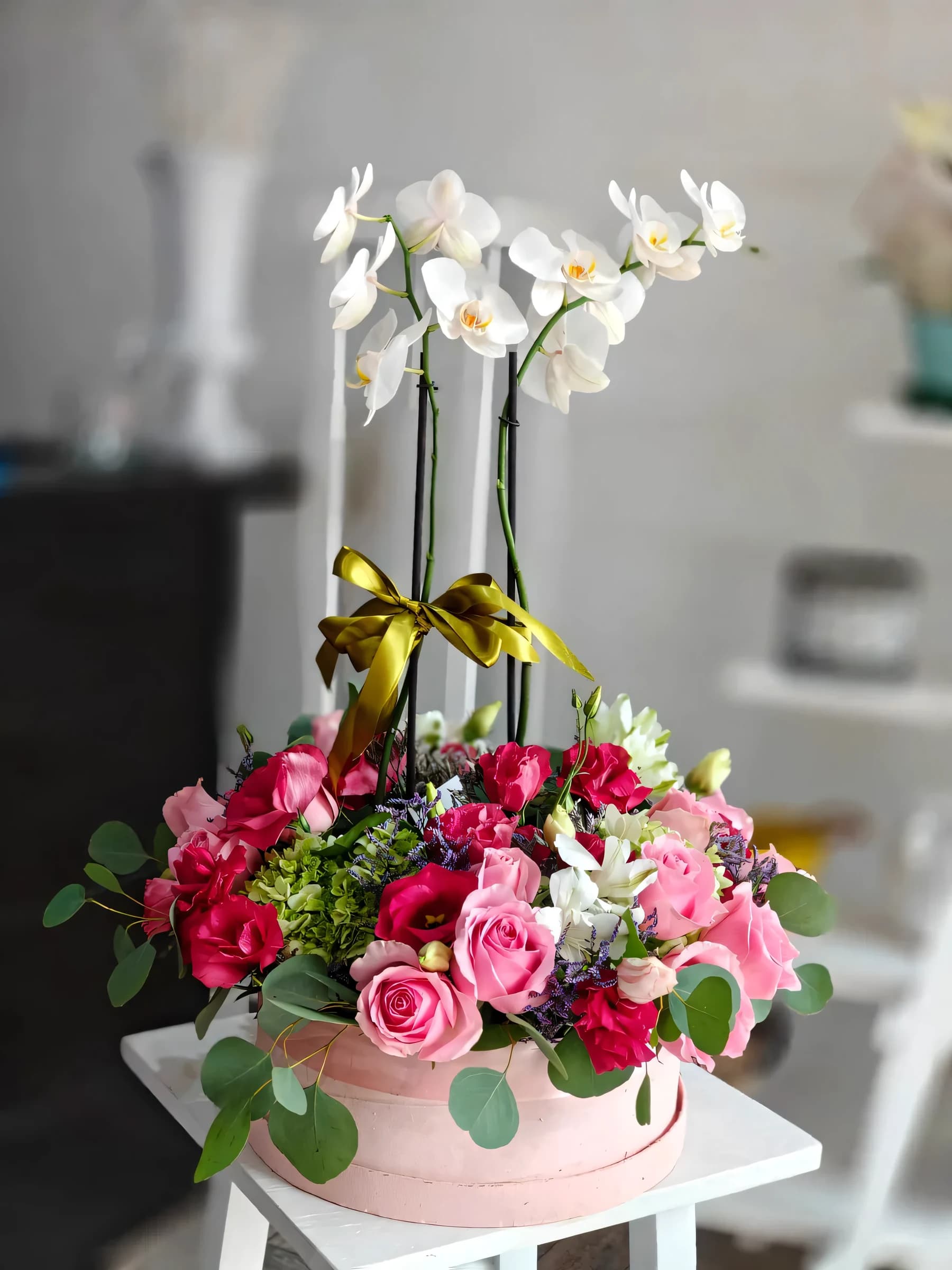 Arreglo con orquídea blanca en caja sombrerera rosa con rosas y hortensia